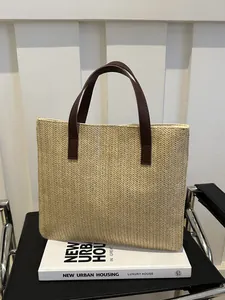 Detail of herringbone weave straw tote bag with elegant dark brown leather handles
