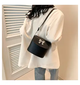Dettaglio di un modello che indossa una borsa a secchiello in pelle nera con fiocco