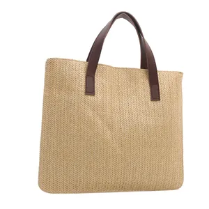 Close-up of beige woven straw tote bag featuring detailed V-shape texture and brown leather handles