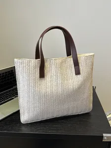 Detailed close-up of woven straw texture and premium brown leather handles on summer tote bag
