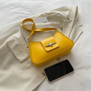 Minimalist bright yellow half-moon underarm bag with a silver star buckle on a blazer