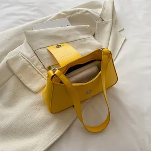 Minimalist bright yellow PU leather underarm bag with silver magnetic buckle on white fabric