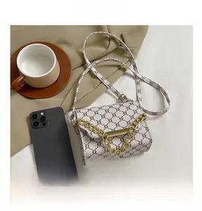 Compact flap crossbody bag showing its mini size compared to a smartphone with golden chain