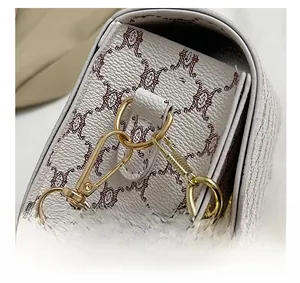 Detail showing the light gold metal hook, D-ring, and chain strap on the white leather bag