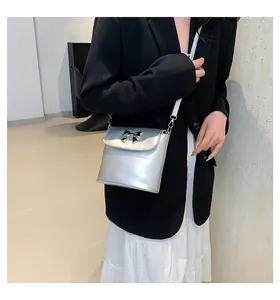 Dettaglio della borsa a tracolla argento metallizzato con fiocco indossata da una modella
