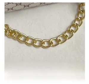 Detailed view of the gold chain handle with polished flat metal links on the square bag