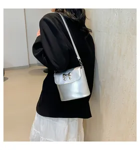 Borsa a secchiello argento con fiocco su modella con texture metallica e finitura