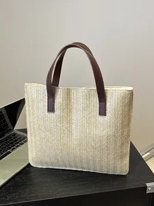 Detailed herringbone weave texture and brown leather handles of this large straw tote bag