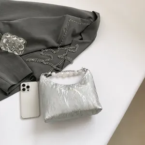 Dettaglio borsa a pieghe argento con trama in metallo liquido e manico in perline