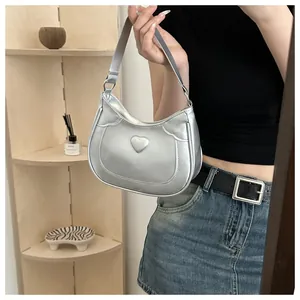 Chic silver crescent hobo bag featuring a 3D heart detail worn by a model in a stylish setting