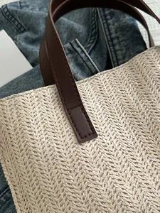 Close-up of woven raffia texture and brown leather handle stitching on a beach tote