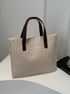 Close-up of V-shaped straw weave texture and brown leather handles on large beach bag