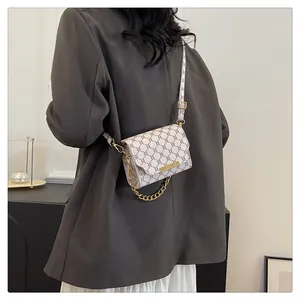 Detail of vintage patterned crossbody bag with gold chain and monogram design