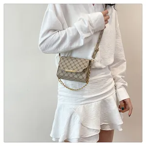Close-up of vintage patterned crossbody bag with gold metal buckle on white dress