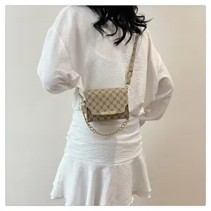 Detail of vintage canvas mini crossbody bag with gold chain and retro geometric pattern