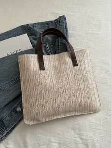 Detailed top view of handmade woven straw tote bag with brown faux leather handles