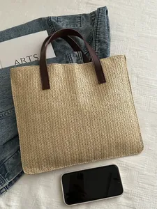 Detailed V-shaped woven straw texture on large beige beach tote with brown leather handles