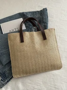 Detailed close-up of woven herringbone pattern and brown leather handles on summer tote bag