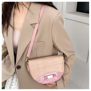 Detail of pink woven saddle bag with metal buckle worn with a khaki suit