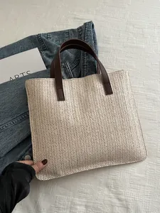 Detail of V-shaped woven texture on beige straw tote bag with brown leather handles