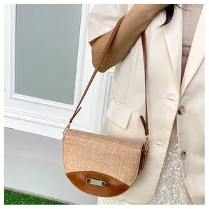 Detail of hand-woven straw saddle bag featuring premium brown leather trim and gold buckle
