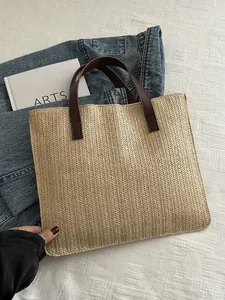 Detail of the woven texture and brown leather handles on a summer straw tote bag