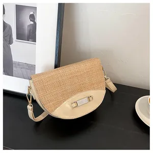 Close-up of woven straw saddle bag with cream leather trim and metal clasp
