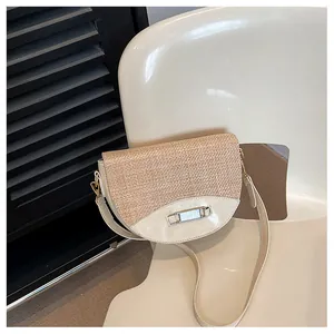 Detail of woven straw texture and faux leather on the minimalist saddle crossbody bag