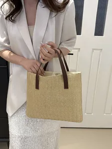 Detailed close-up of straw woven tote with brown leather handles and magnetic closure