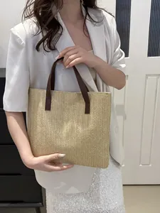 Close-up of beige woven straw tote bag featuring herringbone texture and brown leather straps