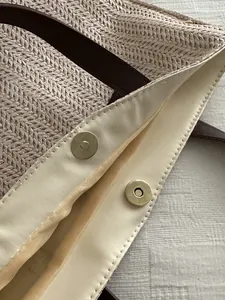 Detail shot of woven straw tote bag featuring magnetic closure and herringbone pattern texture