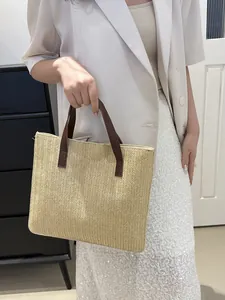 Close-up of straw woven tote bag featuring herringbone texture and brown faux leather handles