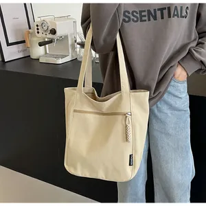 Detail view of beige canvas tote bag with functional zipper pocket and fashion label
