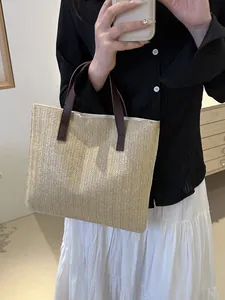 Detail of hand-woven straw tote bag with brown leather handles and textured chevron pattern
