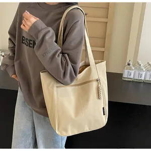 Close-up of beige canvas tote bag with functional front zipper pocket and woven rope puller
