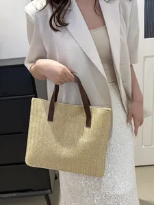 Detail of hand-woven straw tote bag with brown leather handles and herringbone pattern