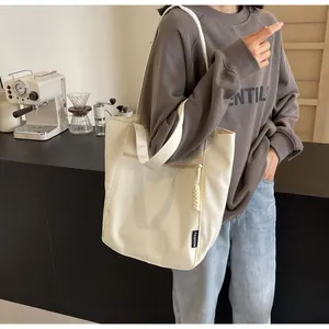 Close-up of cream canvas tote bag with front zipper pocket on a lifestyle model