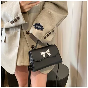 Dettaglio borsa in pelle nera con fiocco in metallo argento e tracolla staccabile