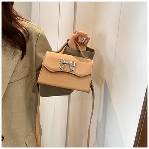 Dettaglio della fibbia a fiocco d'argento su borsa beige in ecopelle chic