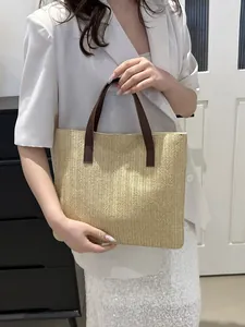 Detail of hand-woven straw tote bag with brown leather handles for summer beach use
