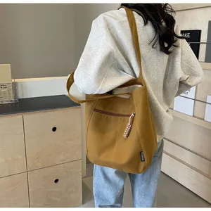 Detail showing brown canvas tote bag with a zipper pocket and a woven zipper puller