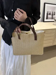 Detail of woven straw bucket bag showing leather handles and secure magnetic closure