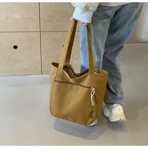 Detail of mustard yellow canvas tote bag featuring front zipper pocket and fashion label