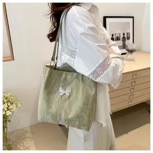 Detail of light green pleated fabric shoulder bag with a white butterfly ornament