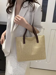 Detail of hand-woven straw tote with brown leather handles worn with a white blazer
