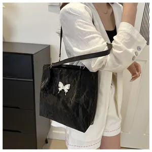 Close-up of black pleated texture shoulder bag with a silver butterfly metal buckle
