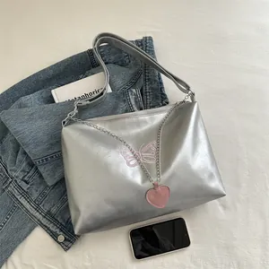 Sac fourre-tout argenté avec broderie papillon rose et pendentif cœur sur fond de jean