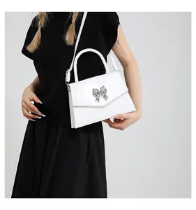 White glossy crossbody bag with silver butterfly buckle shown on model with shoulder strap