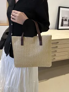 Detail of woven straw tote bag with brown leather handles and textured V-pattern weave