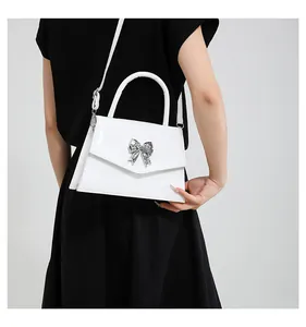 Close-up of a white tote bag with a silver bow and versatile shoulder strap